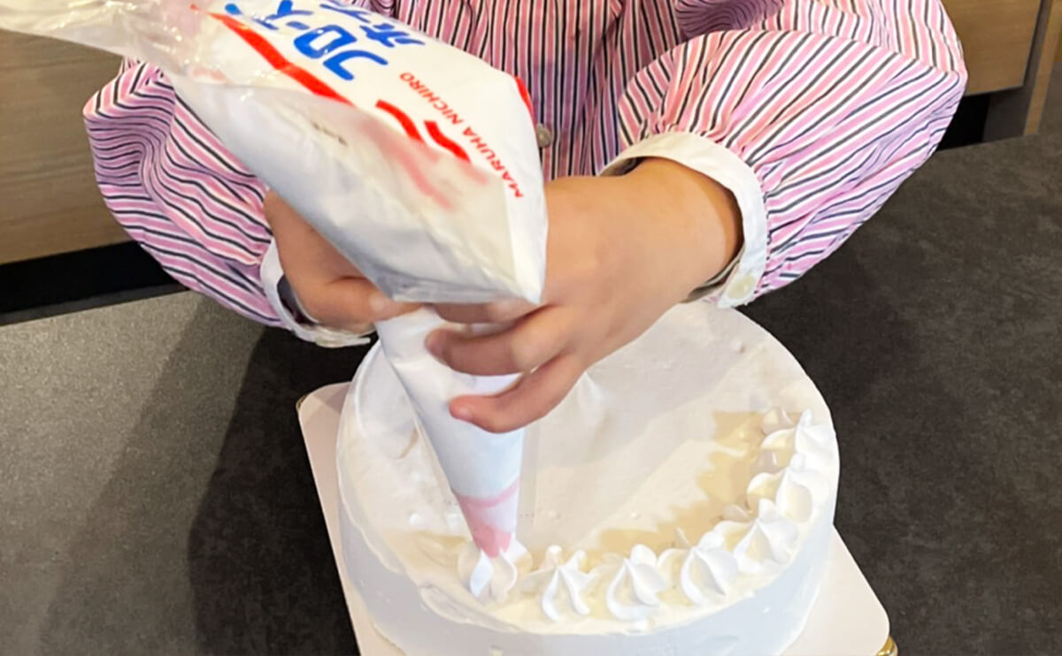デコレーションベースケーキの上に、フローズンホイップクリームを絞っていきます